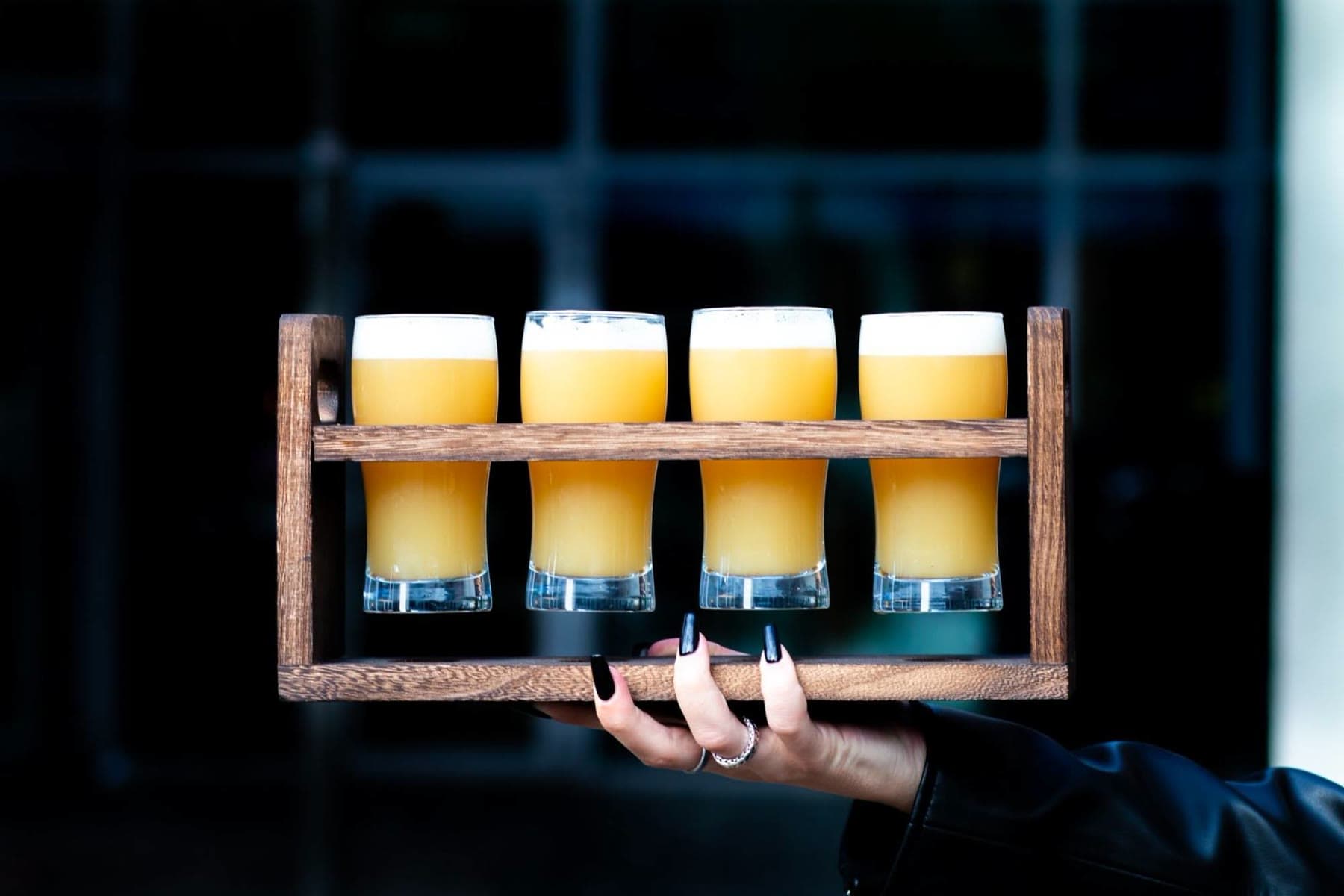 A beer flight: four 15 cl glasses in a wooden rack