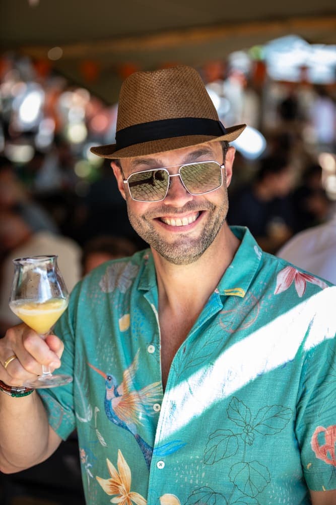 A visitor in a hat and sunglasses raises his glass at Taphorst '26