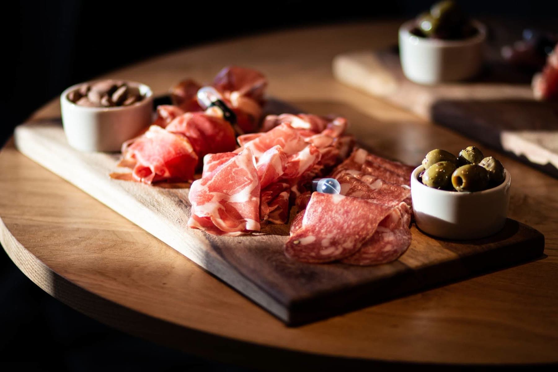 A charcuterie board with olives and almonds on a wooden table